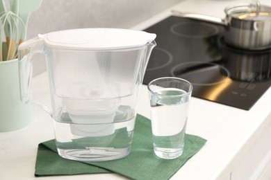 Photo of Water filter jug and glass on white countertop in kitchen