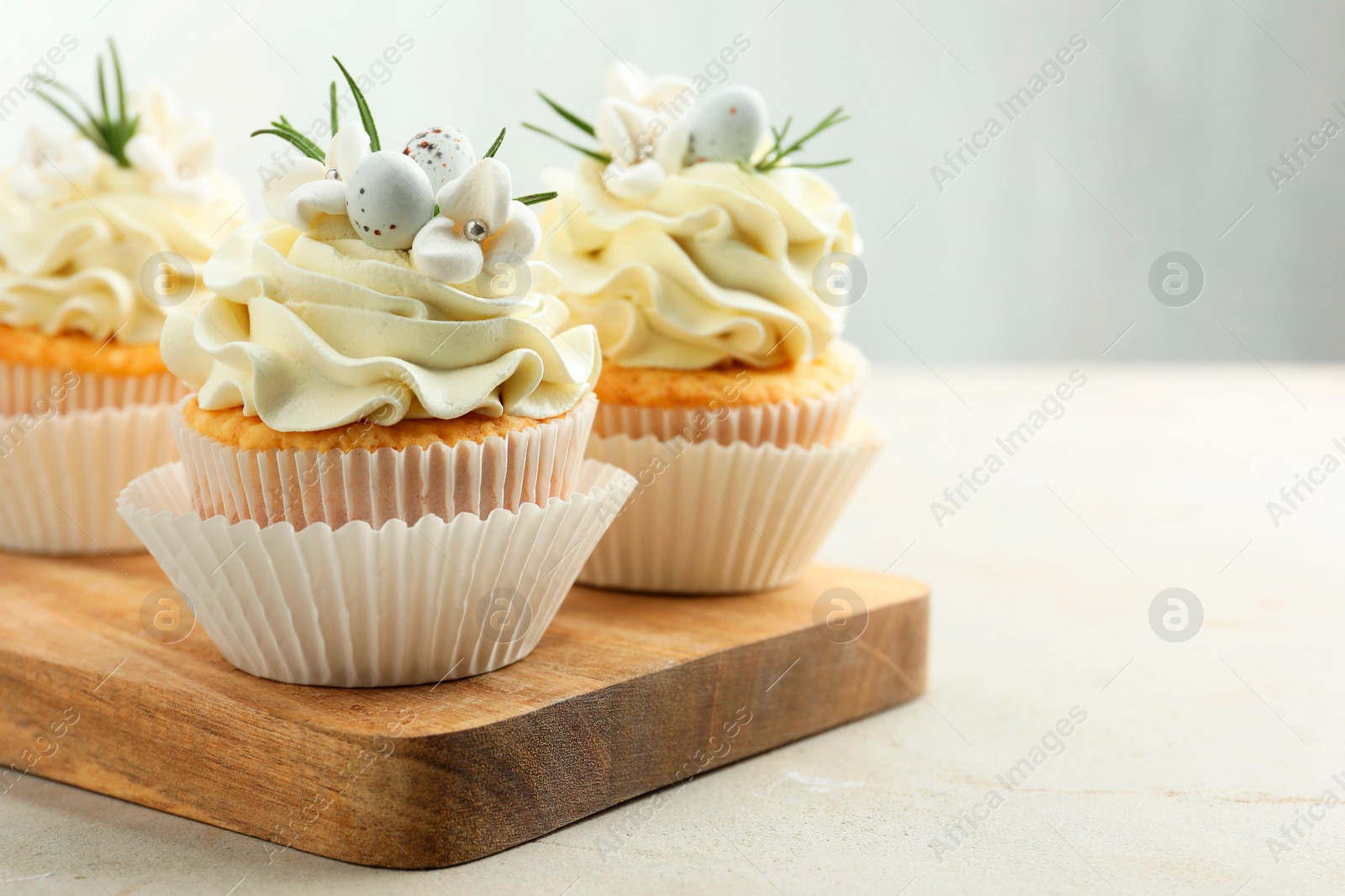 Photo of Tasty Easter cupcakes with vanilla cream on gray table, space for text