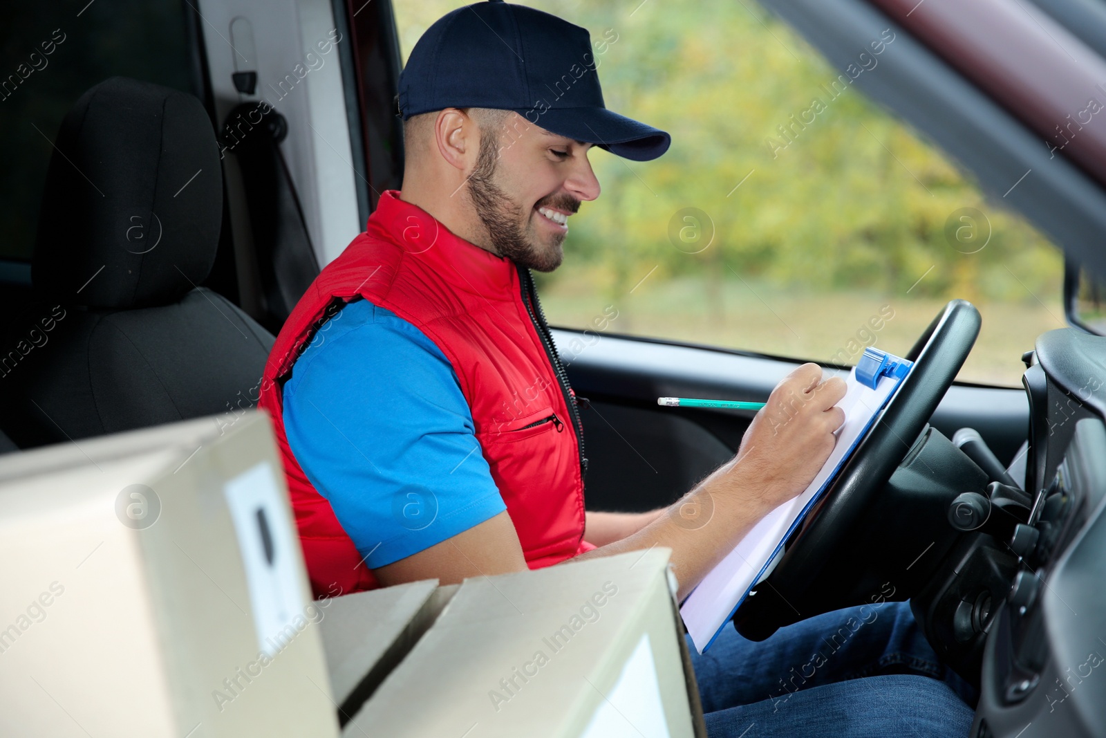 Photo of Young courier checking amount of parcels in delivery van