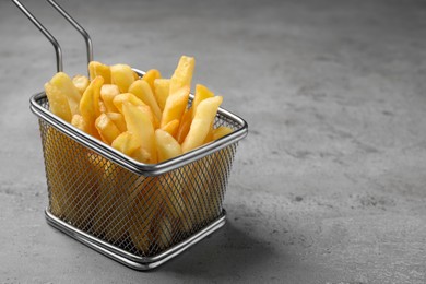 Photo of Frying basket with tasty french fries on light grey table, closeup. Space for text