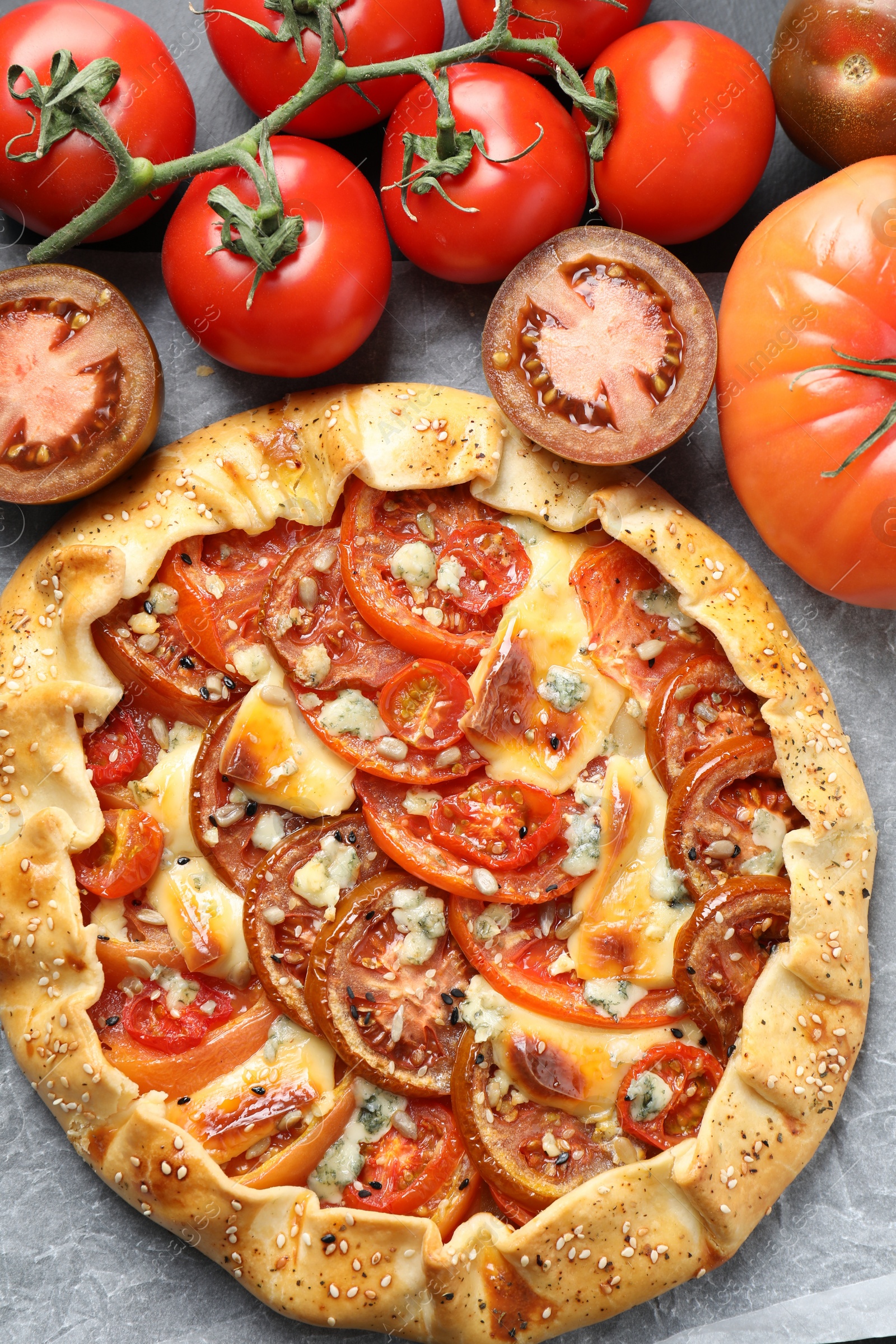 Photo of Tasty galette with tomato and cheese (Caprese galette) on parchment, top view