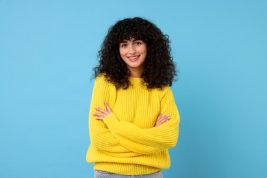 Photo of Happy young woman in stylish yellow sweater on light blue background