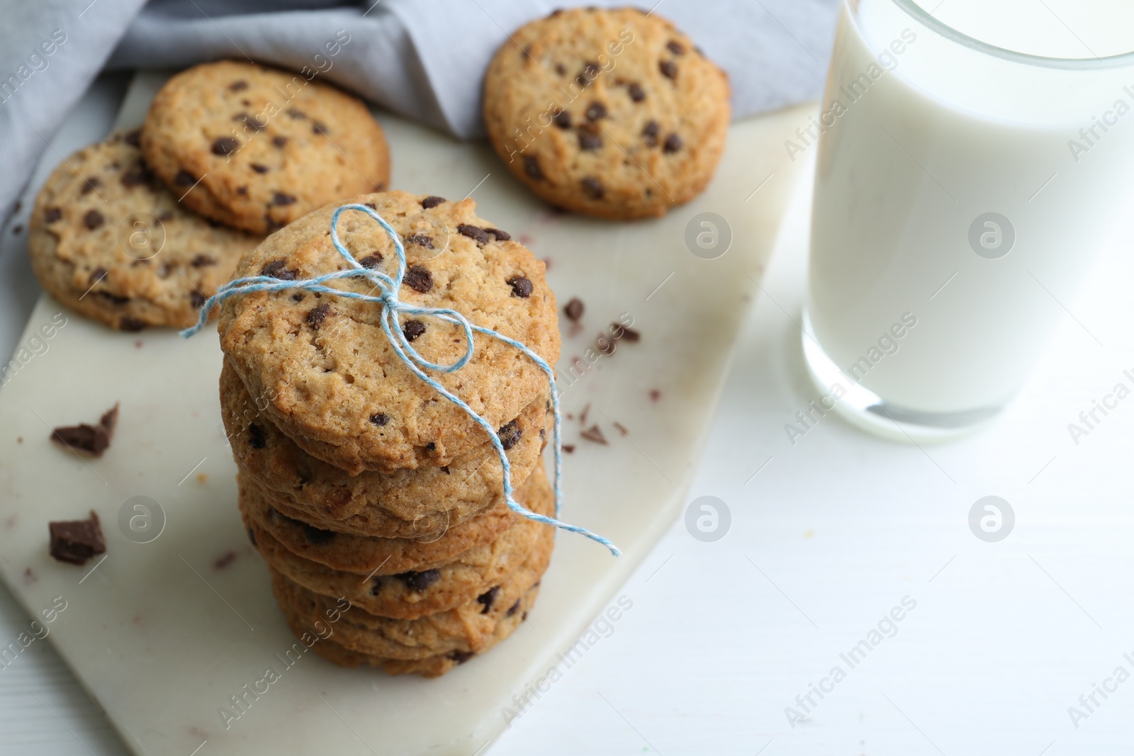 Photo of Tasty chocolate chip cookies and glass of milk on white wooden table, closeup