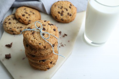 Photo of Tasty chocolate chip cookies and glass of milk on white wooden table, closeup