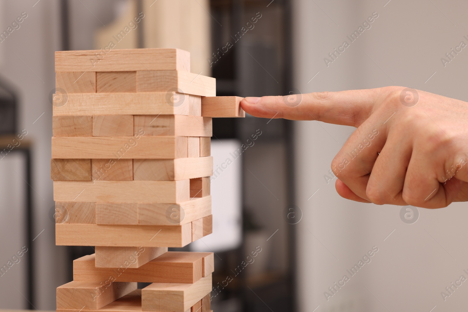 Photo of Playing Jenga. Man building tower with wooden blocks indoors, closeup