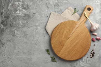 Photo of Cutting board, garlic, spices and rosemary on grey textured table, flat lay. Space for text