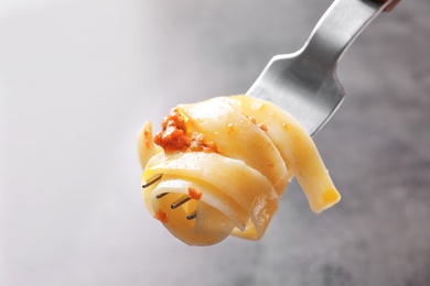 Photo of Fork with delicious pasta bolognese on grey background, closeup