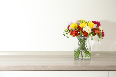 Photo of Beautiful spring freesia flowers in vase on table. Space for text