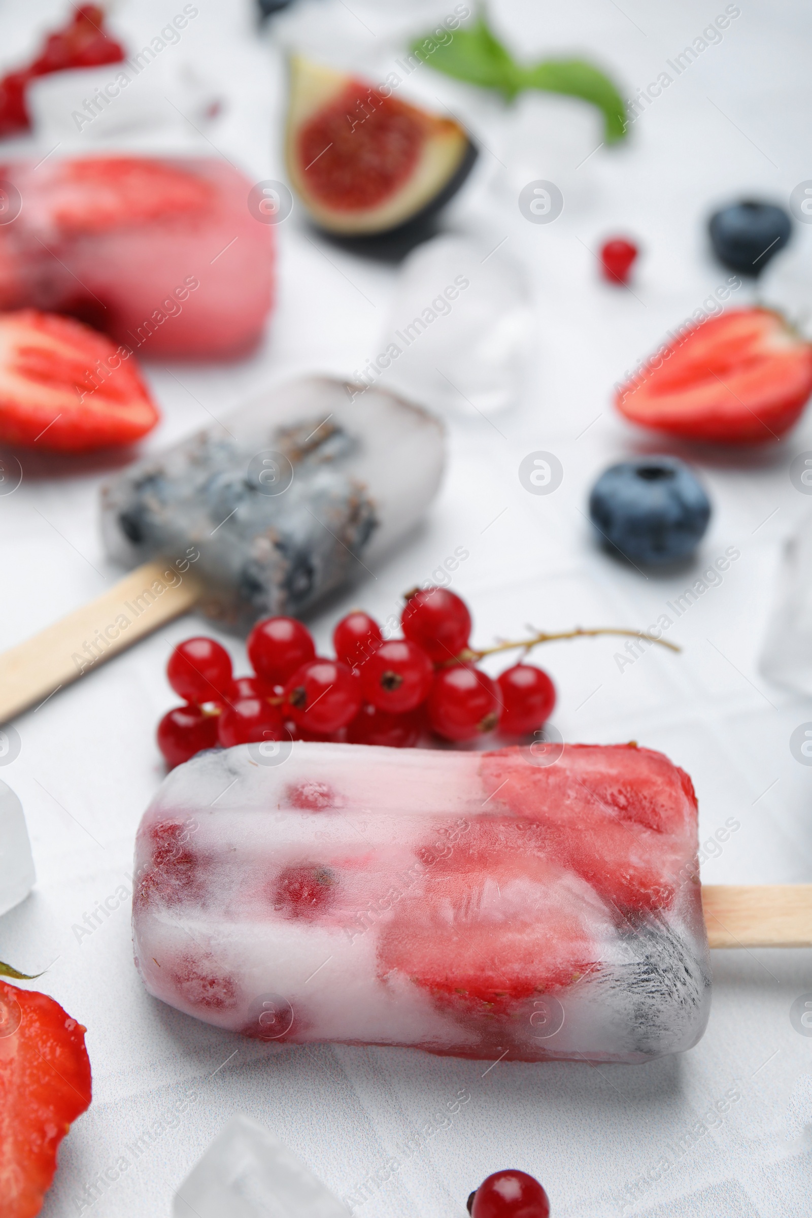 Photo of Tasty refreshing berry ice pops on white table, closeup