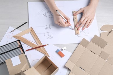 Photo of Woman creating packaging design at light wooden table, above view