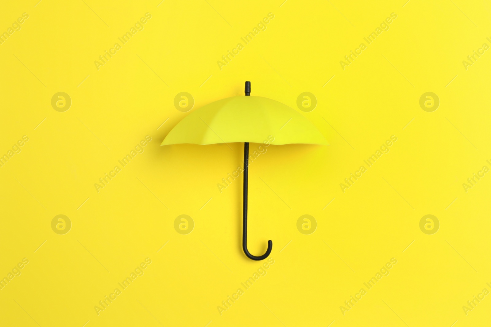 Photo of Bright toy umbrella on yellow background, top view