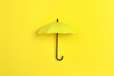 Bright toy umbrella on yellow background, top view