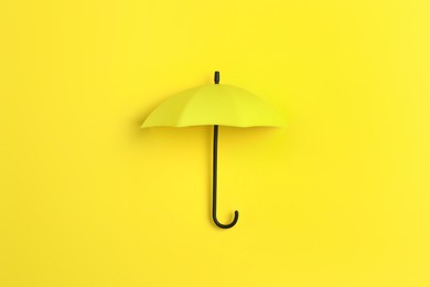 Photo of Bright toy umbrella on yellow background, top view