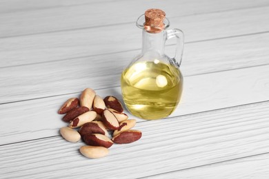 Tasty Brazil nuts and bottle with oil on white wooden table