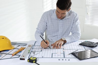 Photo of Architect working with construction drawings in office