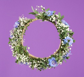 Beautiful handmade flower wreath on purple background