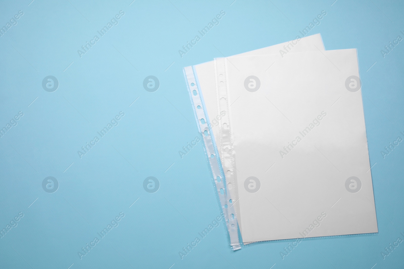 Photo of Punched pockets with paper sheets on turquoise background, flat lay. Space for text