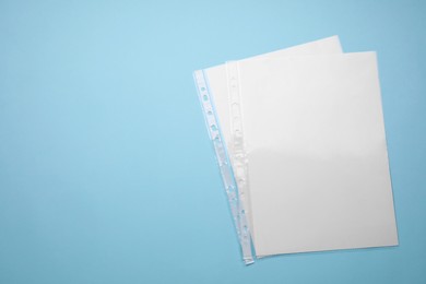 Photo of Punched pockets with paper sheets on turquoise background, flat lay. Space for text