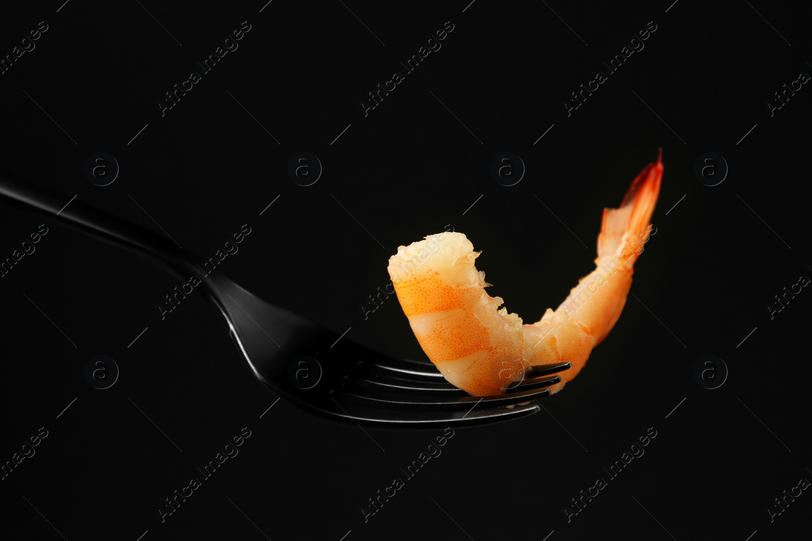 Photo of Fork with tasty shrimp on black background