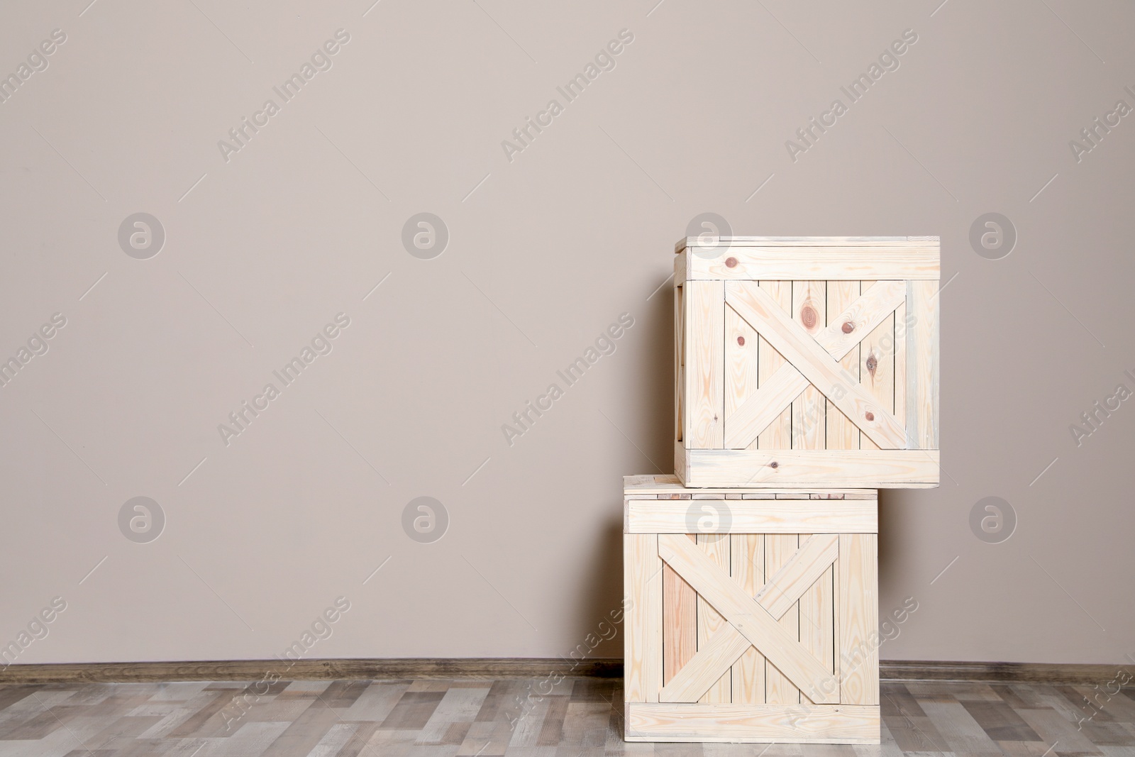 Photo of Wooden crates on floor at beige wall. Space for text