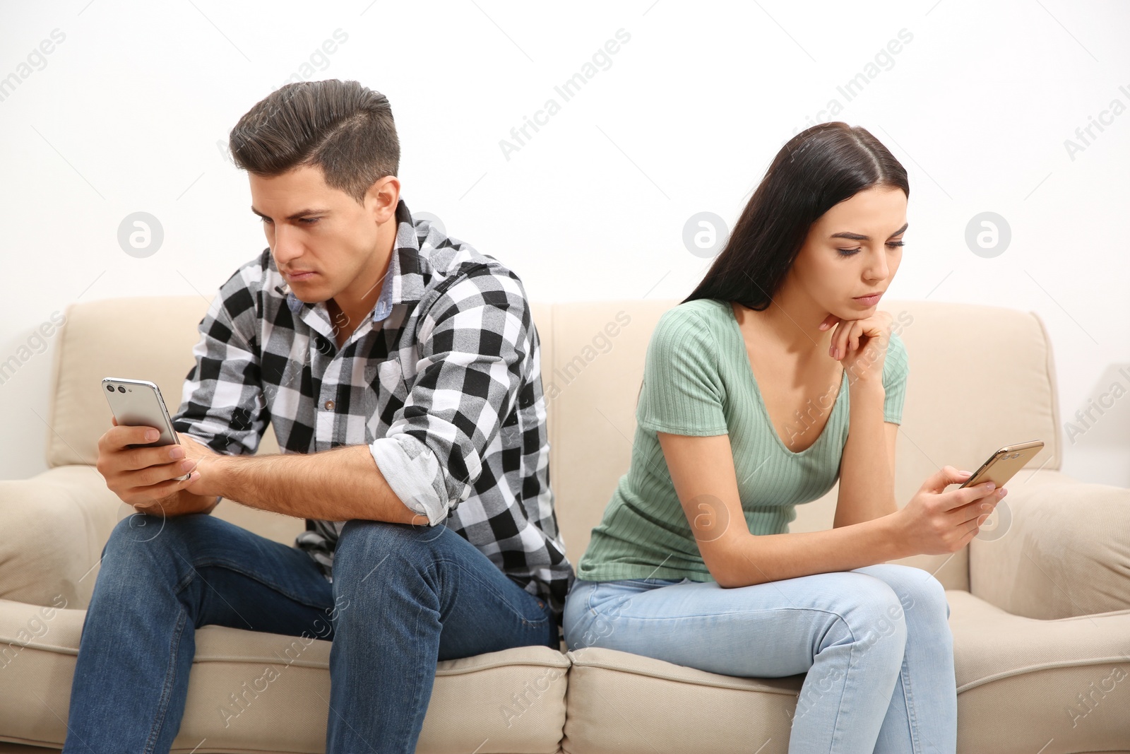 Photo of Couple addicted to smartphones ignoring each other at home. Relationship problems