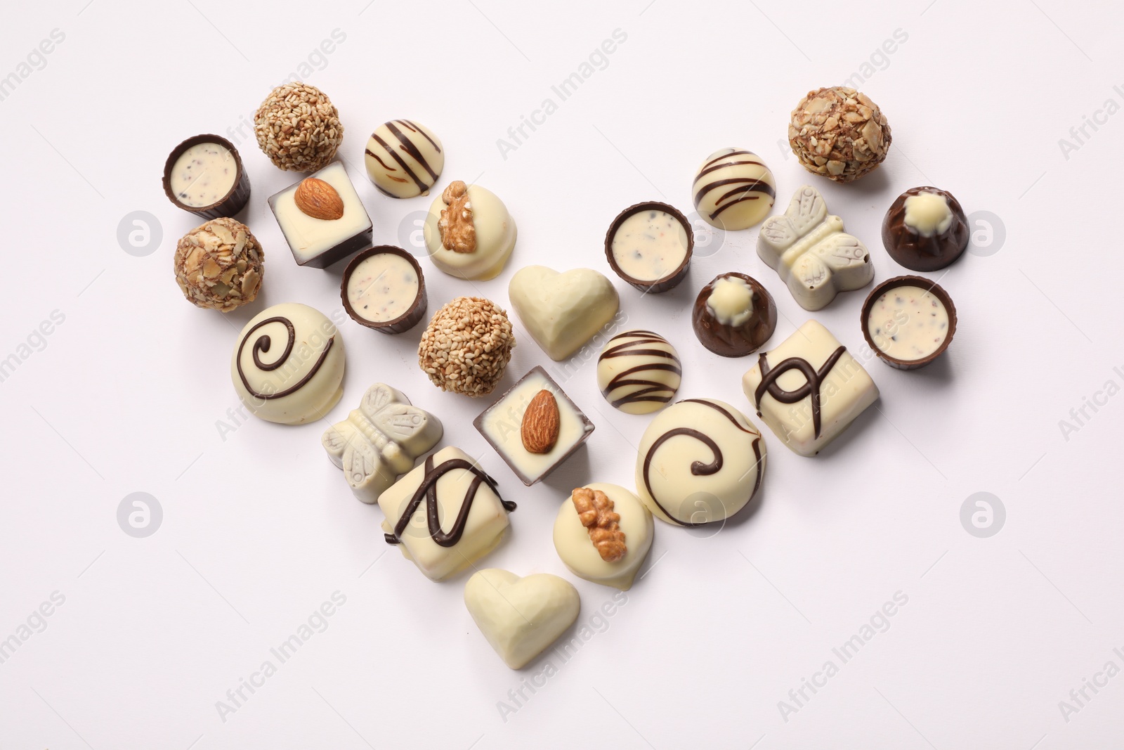 Photo of Heart made with delicious chocolate candies on white background, above view