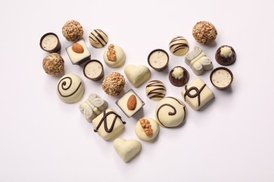 Photo of Heart made with delicious chocolate candies on white background, above view