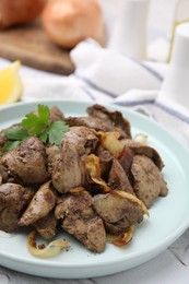 Photo of Tasty fried chicken liver with onion and parsley on white table, closeup