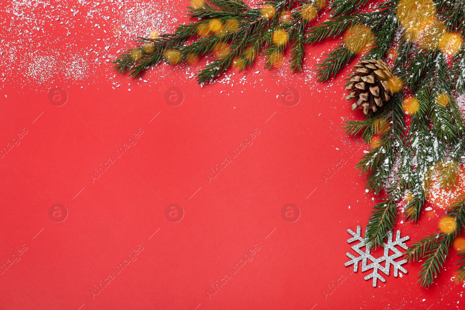 Photo of Christmas greeting card with space for text. Flat lay composition of fir tree branches and festive decor on red background