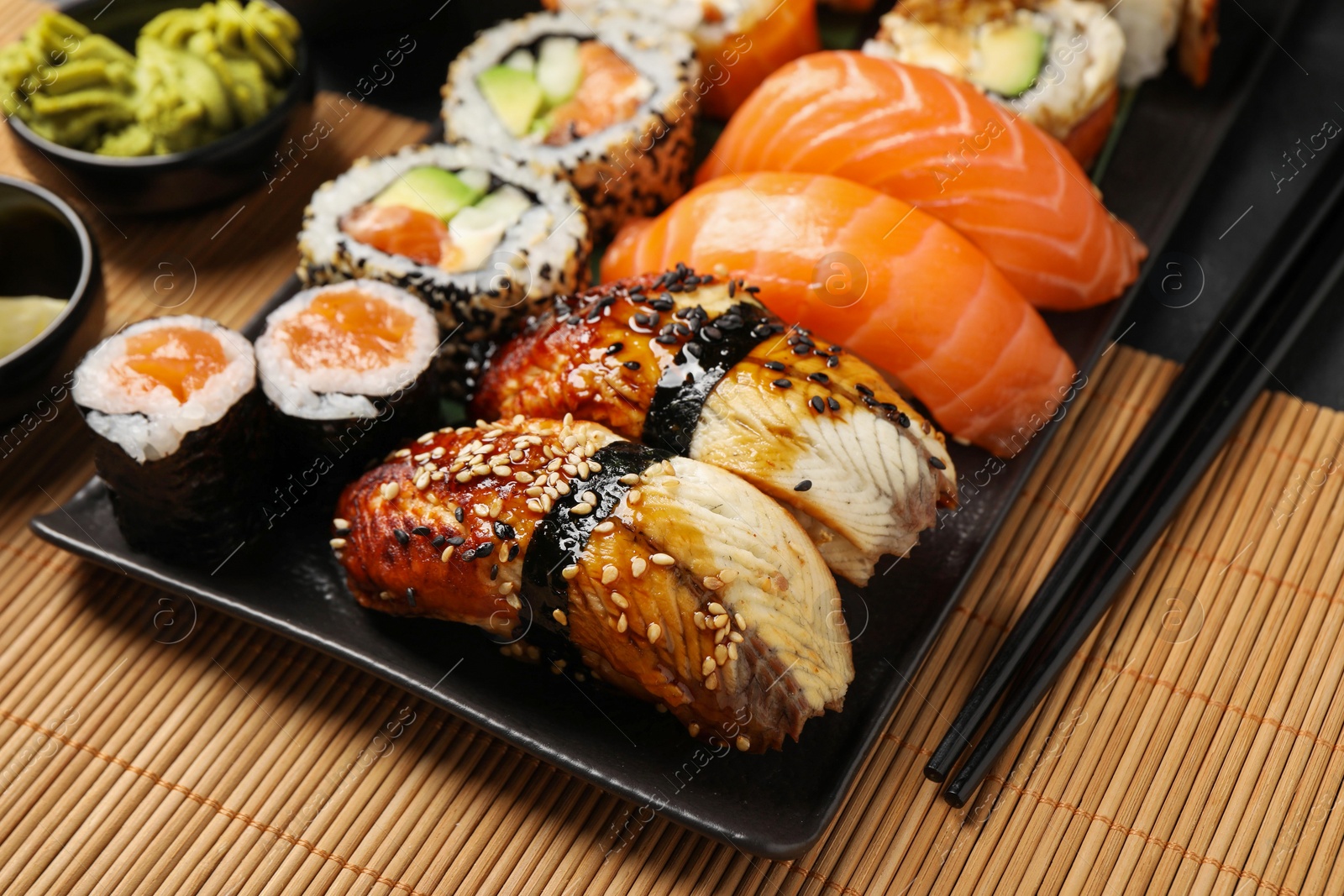 Photo of Set of delicious sushi rolls on mat, closeup