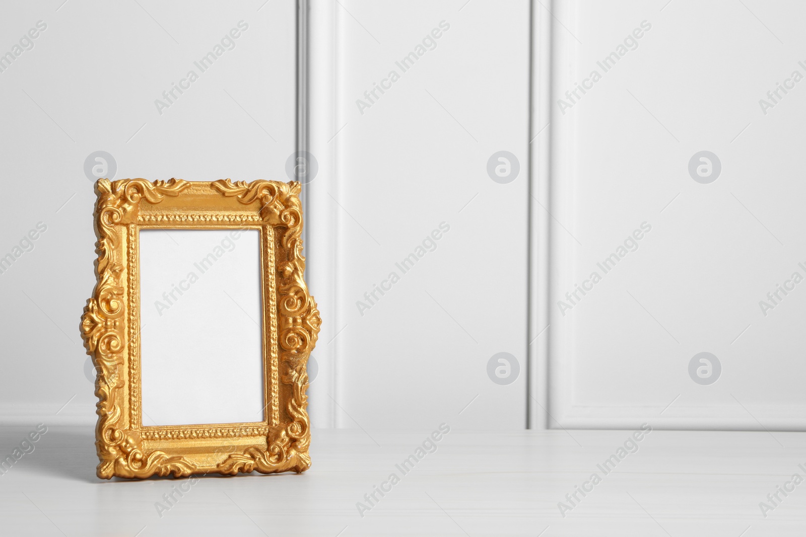 Photo of Empty photo frame on white wooden table indoors, space for text