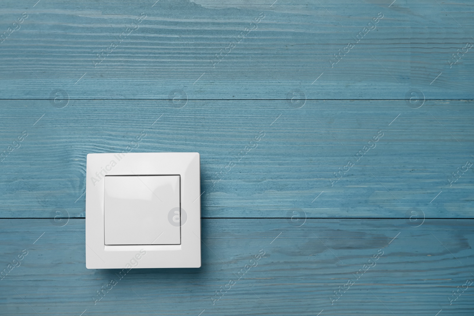 Photo of White light switch on turquoise wooden background. Space for text