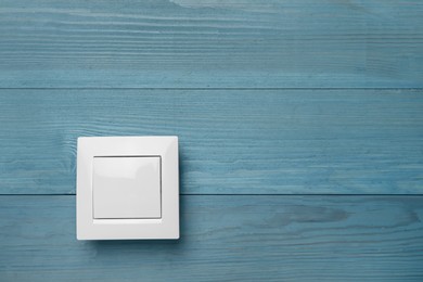 Photo of White light switch on turquoise wooden background. Space for text