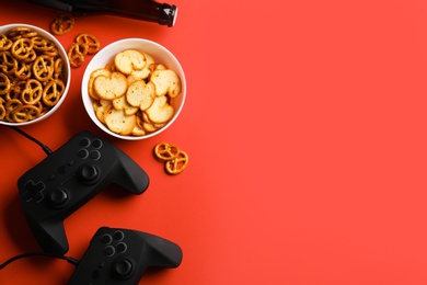 Flat lay composition with video game controllers, snacks and space for text on color background