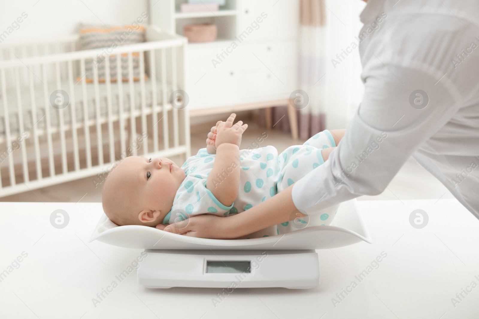 Photo of Doctor weighting baby on scales in light room