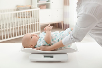 Photo of Doctor weighting baby on scales in light room