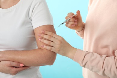 Photo of Diabetes. Woman getting insulin injection on light blue background, closeup