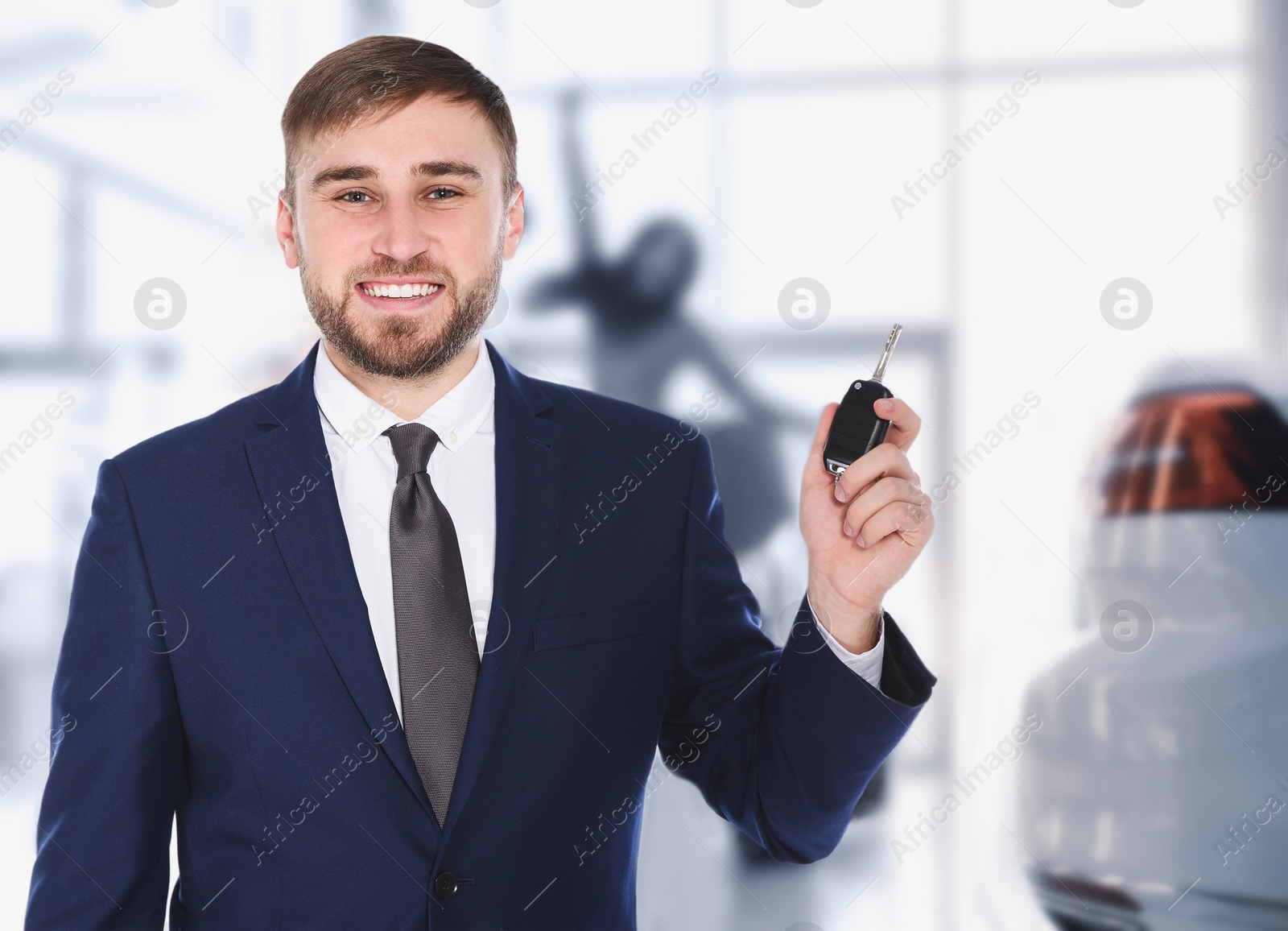 Image of Happy salesman with key in car salon