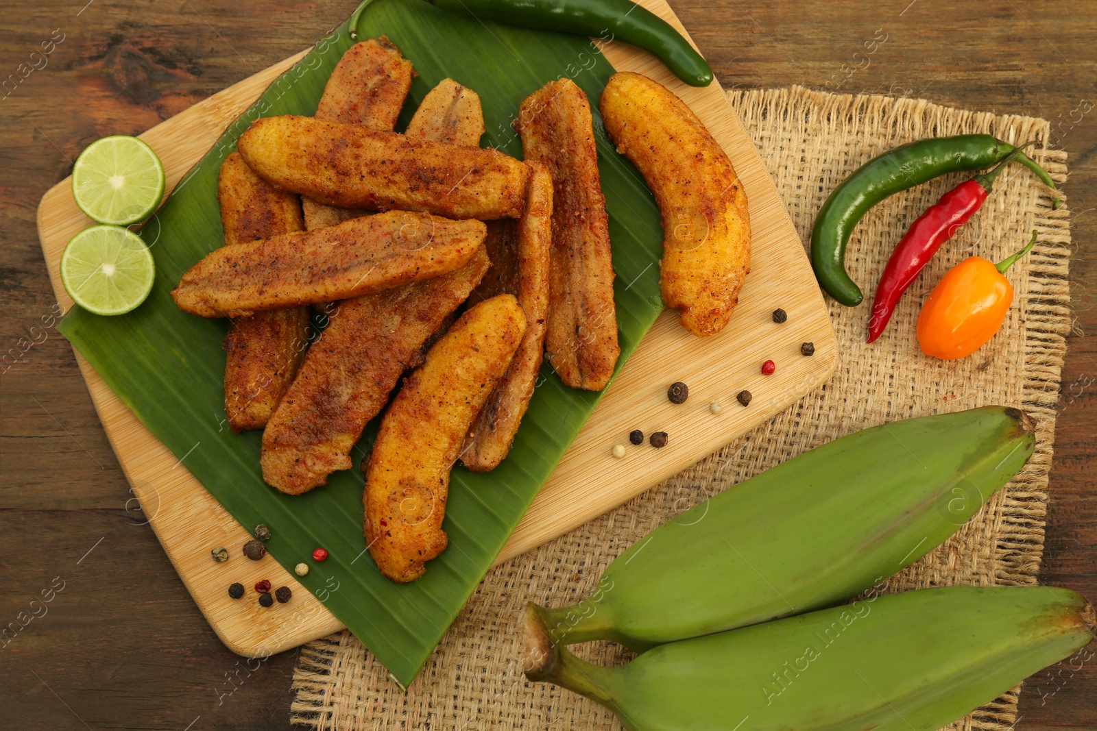 Photo of Delicious fried bananas, fresh fruits and different peppers on wooden table, flat lay