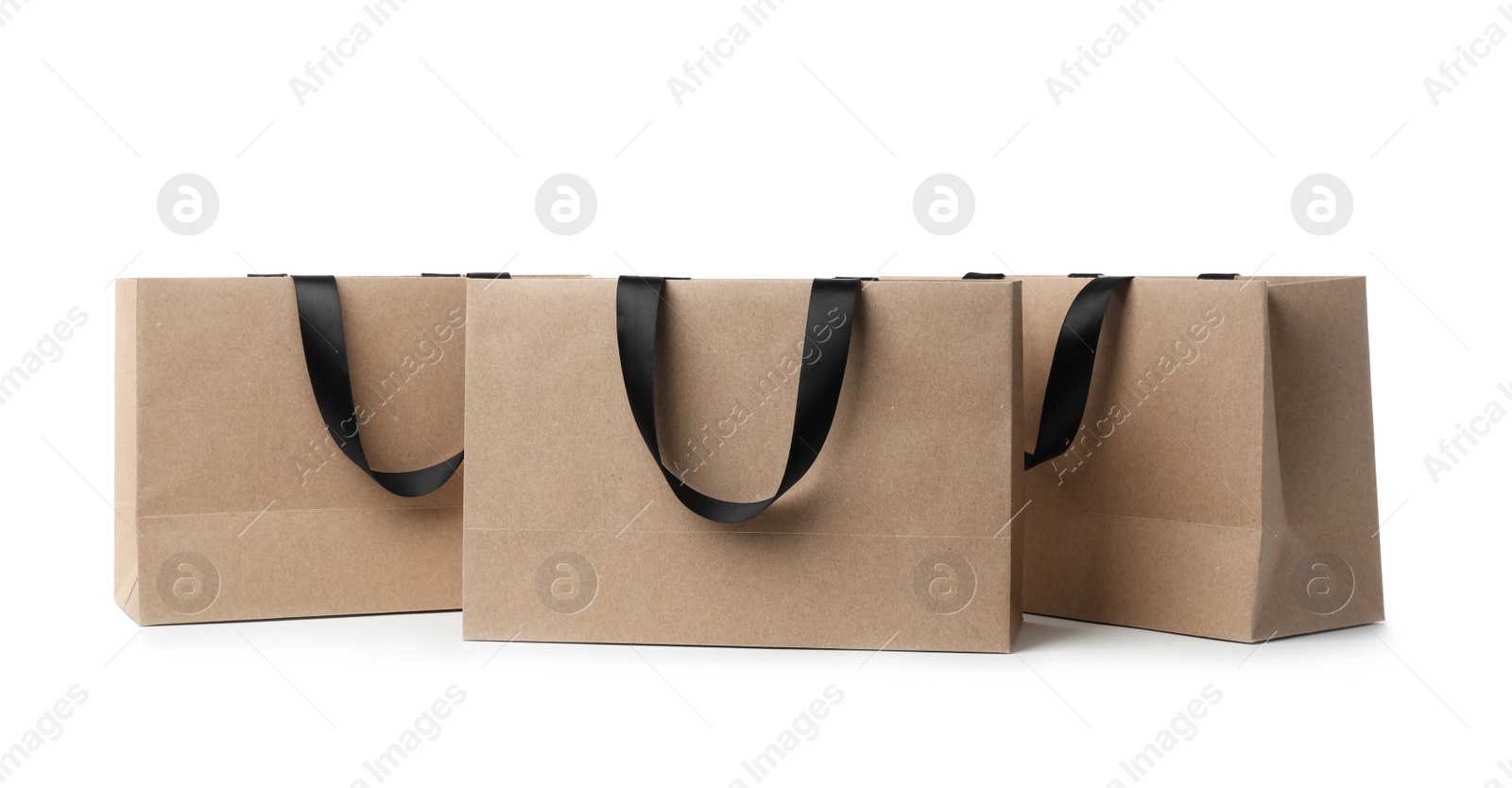 Photo of Paper shopping bags with ribbon handles on white background. Mockup for design