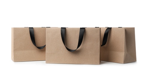 Photo of Paper shopping bags with ribbon handles on white background. Mockup for design