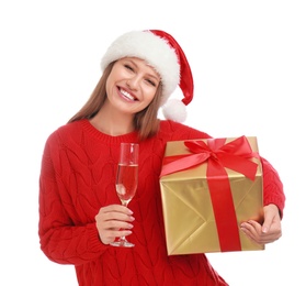 Photo of Happy young woman in Santa hat with Christmas gift and glass of champagne on white background