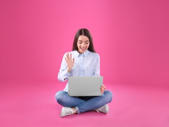 Photo of Woman using laptop for video chat on color background