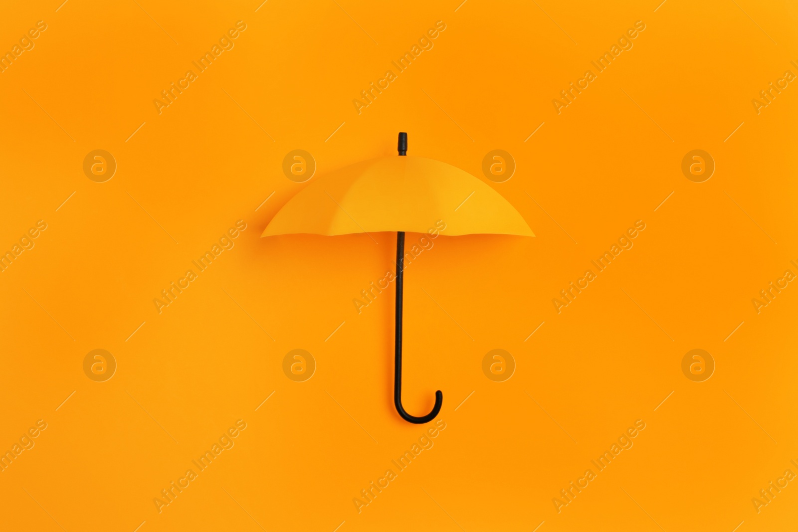 Image of Bright toy umbrella on orange background, top view