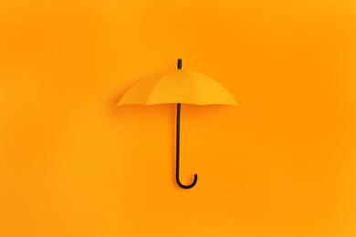 Image of Bright toy umbrella on orange background, top view