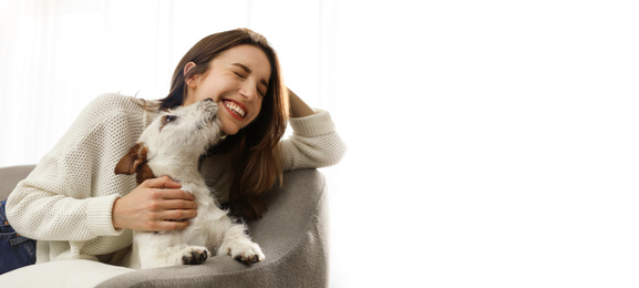 Young woman with her cute pet at home, space for text. Banner design