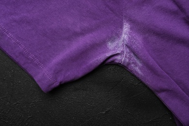 Photo of T-shirt with deodorant stain on black background, closeup