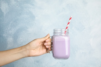Photo of Woman with mason jar of delicious milk shake on color background, closeup