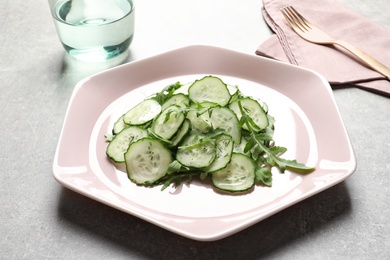 Photo of Plate with delicious cucumber salad served on grey table