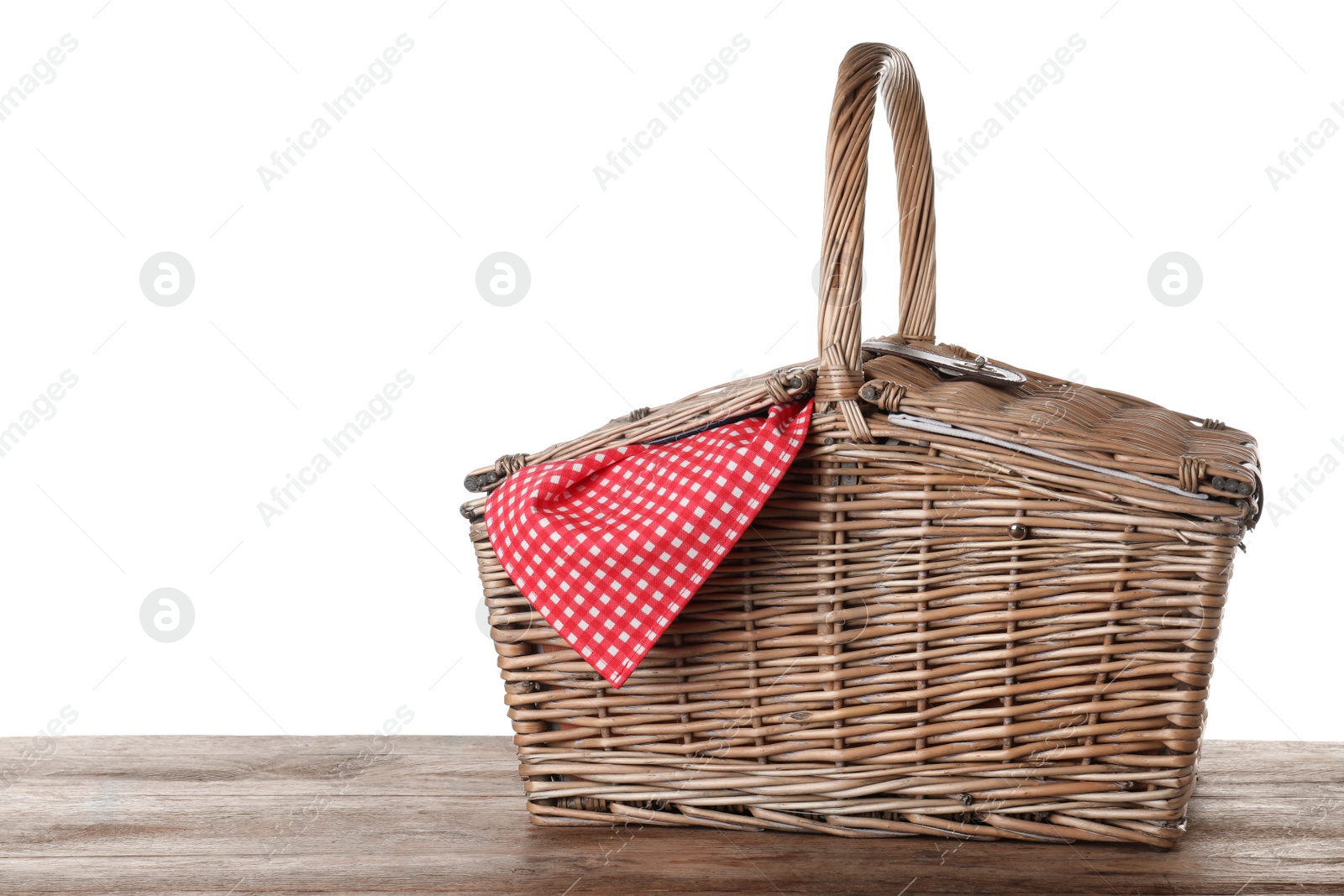 Photo of Closed wicker picnic basket with checkered tablecloth on wooden table against white background